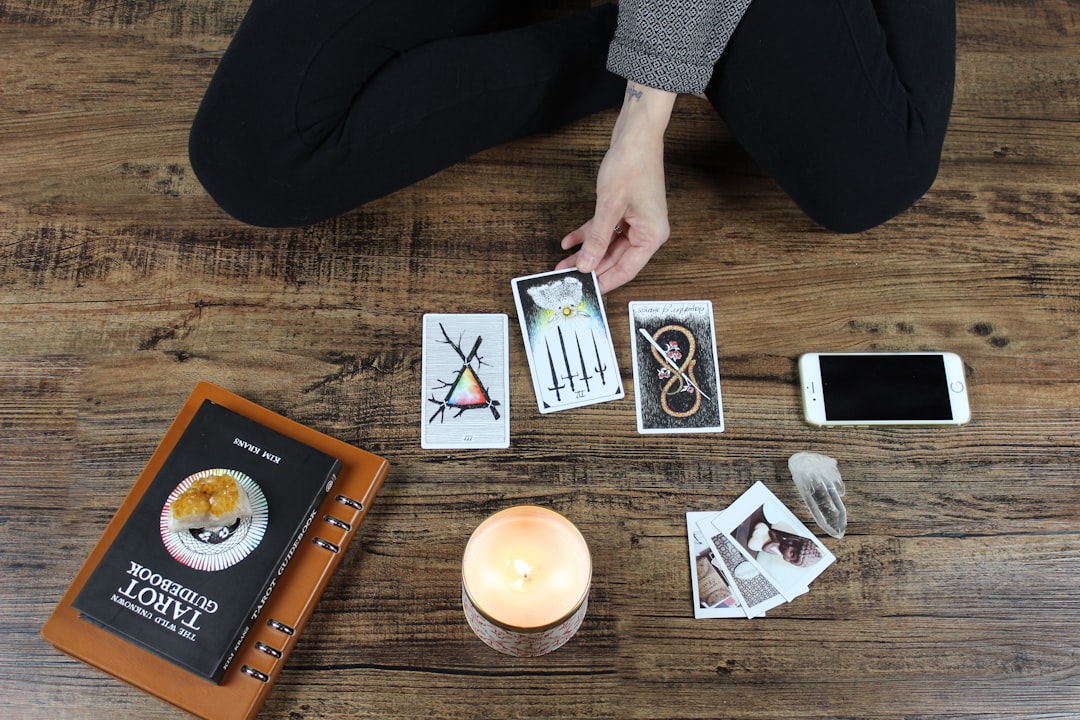 Three tarot cards laid out beside a candle, guidebook and crystal