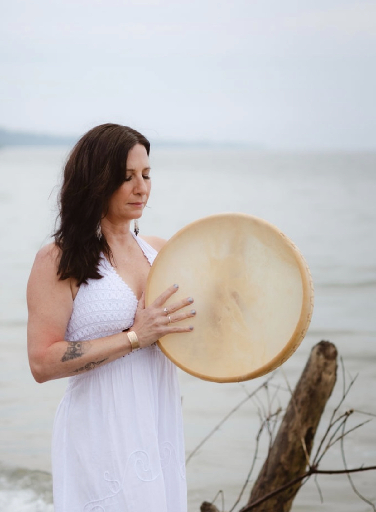 Miche holding a ceremonial drum by the water