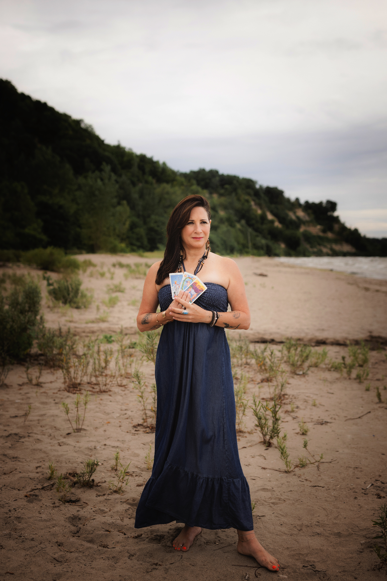 Miche holding tarot cards by the shoreline